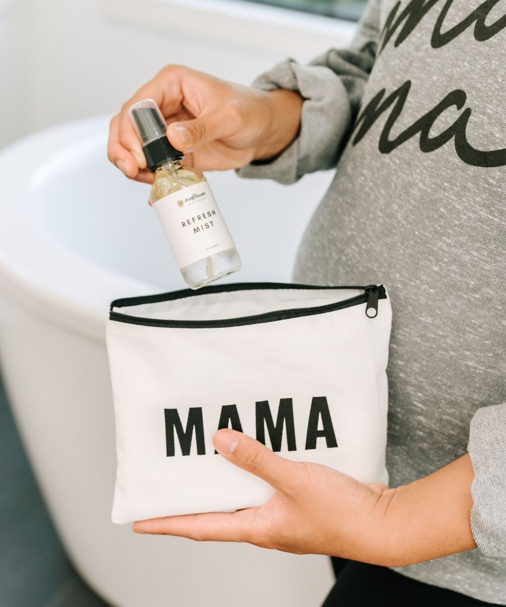 A woman holding a white bag with the word "mama" on it, symbolizing motherhood and carrying essentials.