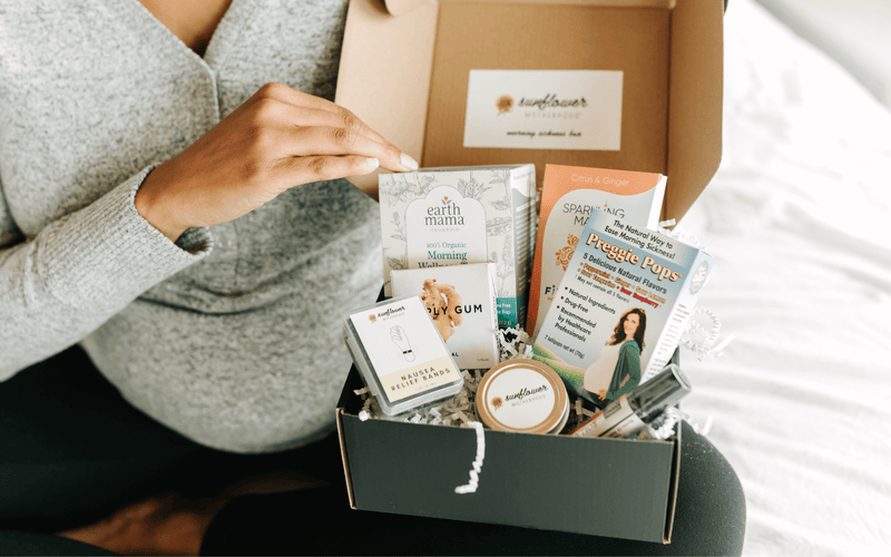 A woman sitting down, holding a box of products in her lap.