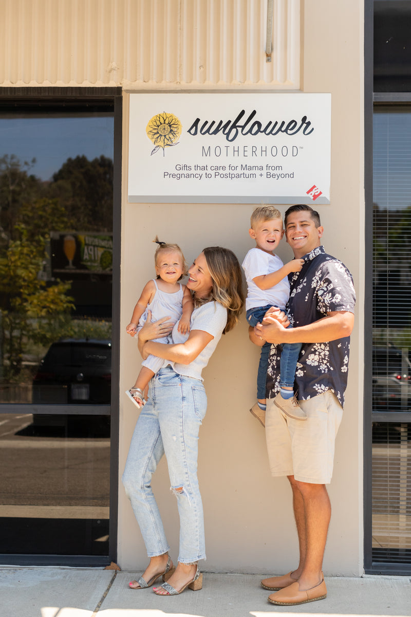 A happy family of four smiling and posing together in a park on a sunny day.