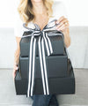 A woman holding a black and white striped gift box.