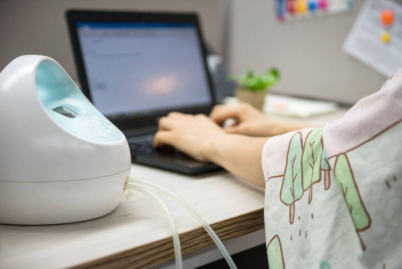 A person using a laptop with a humidifier in the background