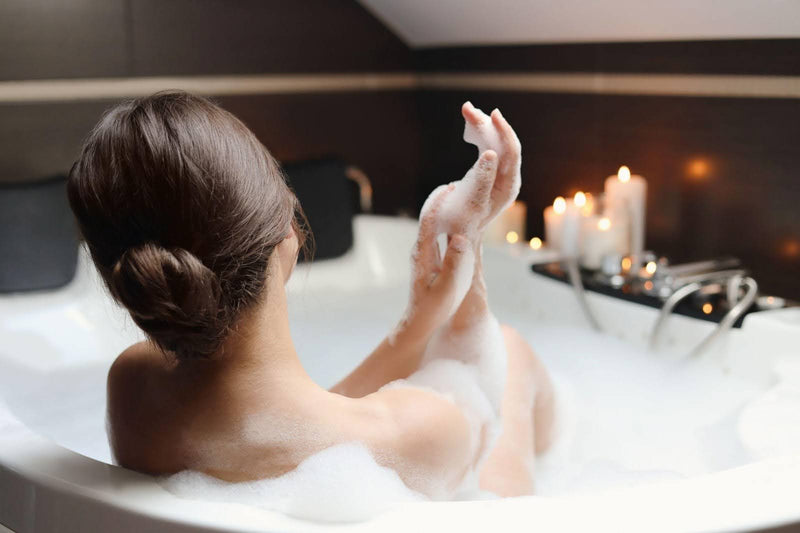 A woman enjoys a peaceful moment in a bathtub surrounded by soft candlelight