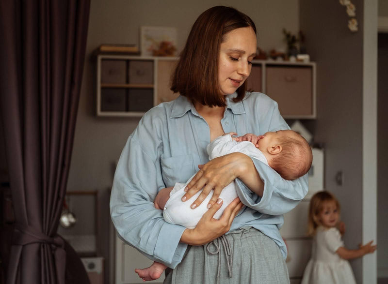 A woman lovingly carries a baby in her arms highlighting a bond of tenderness and maternal care