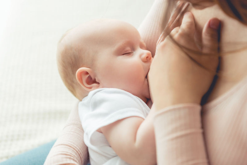 Mother breastfeeding her newborn baby in a serene close-up, with the infant peacefully nursing and eyes closed