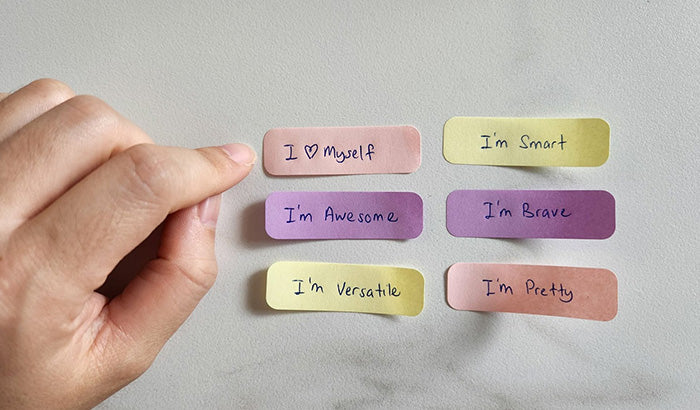 Person holding paper with sticky notes: Daily affirmations for mom, motherhood affirmations.