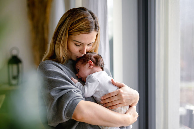 Woman holding a baby in a softly lit room