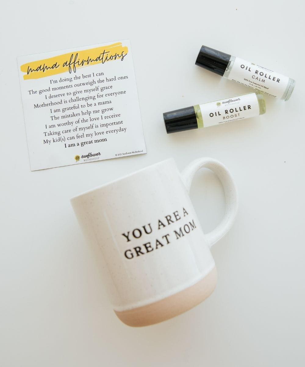 a note for affirmations and oil roller with a white mug