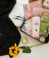 A black hoodie, sunflowers, and various items neatly arranged in a box.
